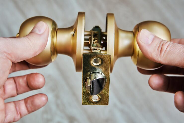 door-knob-held-by-hands-showcases-latch-mechanism-brass-finish-revealing-workings-typical-door-handle-against-neutral-background-secure-key-pros